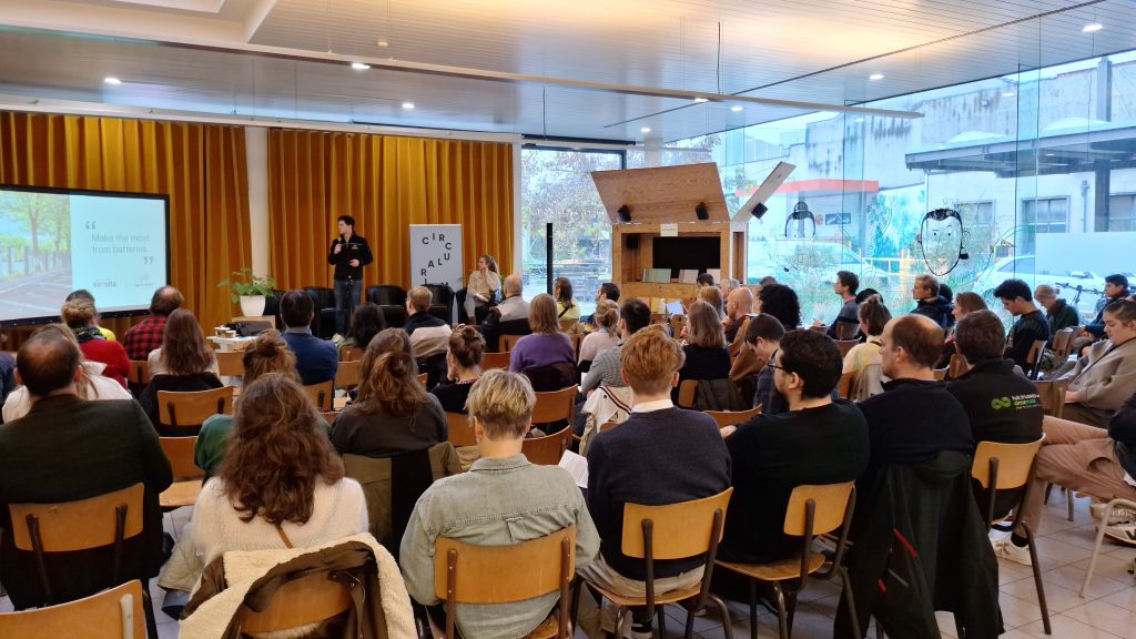 Photo showing a conference room with participants listening to the presentation about circularity in battery production, use and disposal, delivered by Aimilios Orfanos, CEO of Watt4Ever, Belgian company specialised in the development of innovative solutions for energy storage and management. 